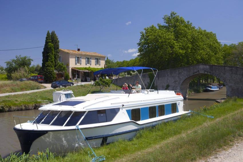 Barcos cruceros fluviales | Danfluvial Un barco fluvial navegando por las tranquilas aguas del Canal du Midi.
