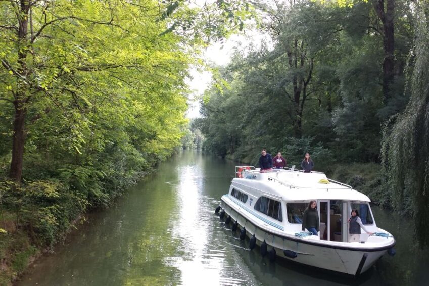 CHARENTE 16 1024x576 1 Barco de alquiler sin licencia navegando por un canal estrecho rodeado de arboles en el rio Charente